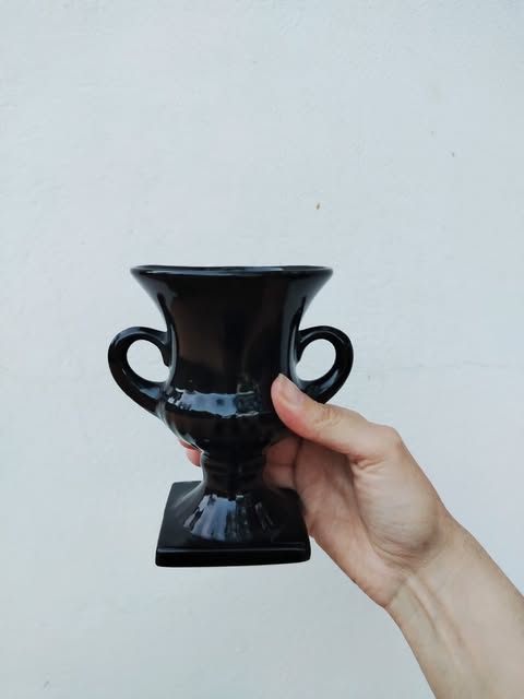 A black two-handled vase held in a hand