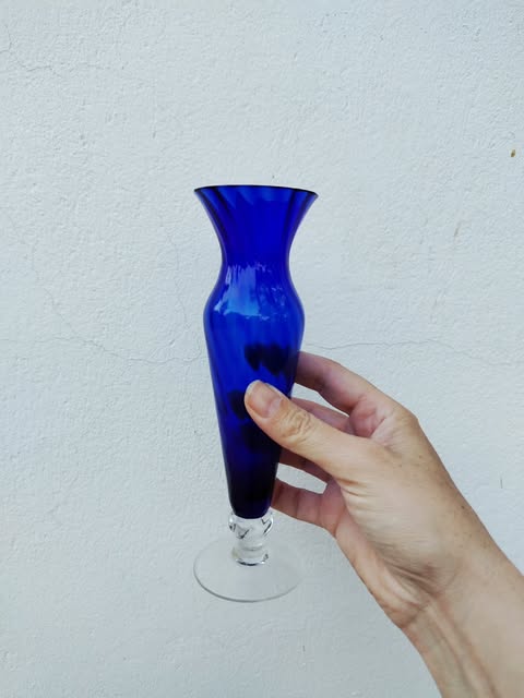 A cobalt blue glass vase held in a hand