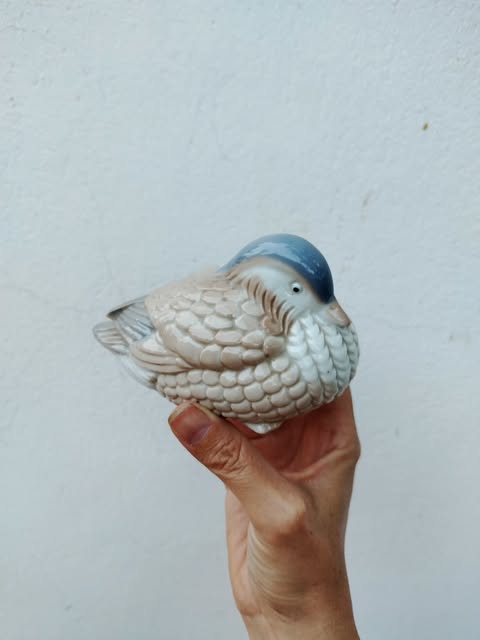 A small ceramic bird held in a hand