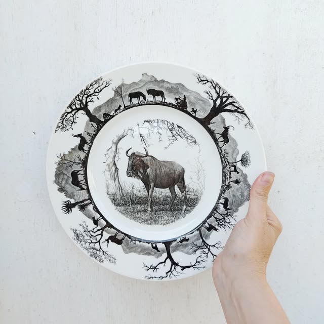 A black and white wildebeest collector plate held in a hand